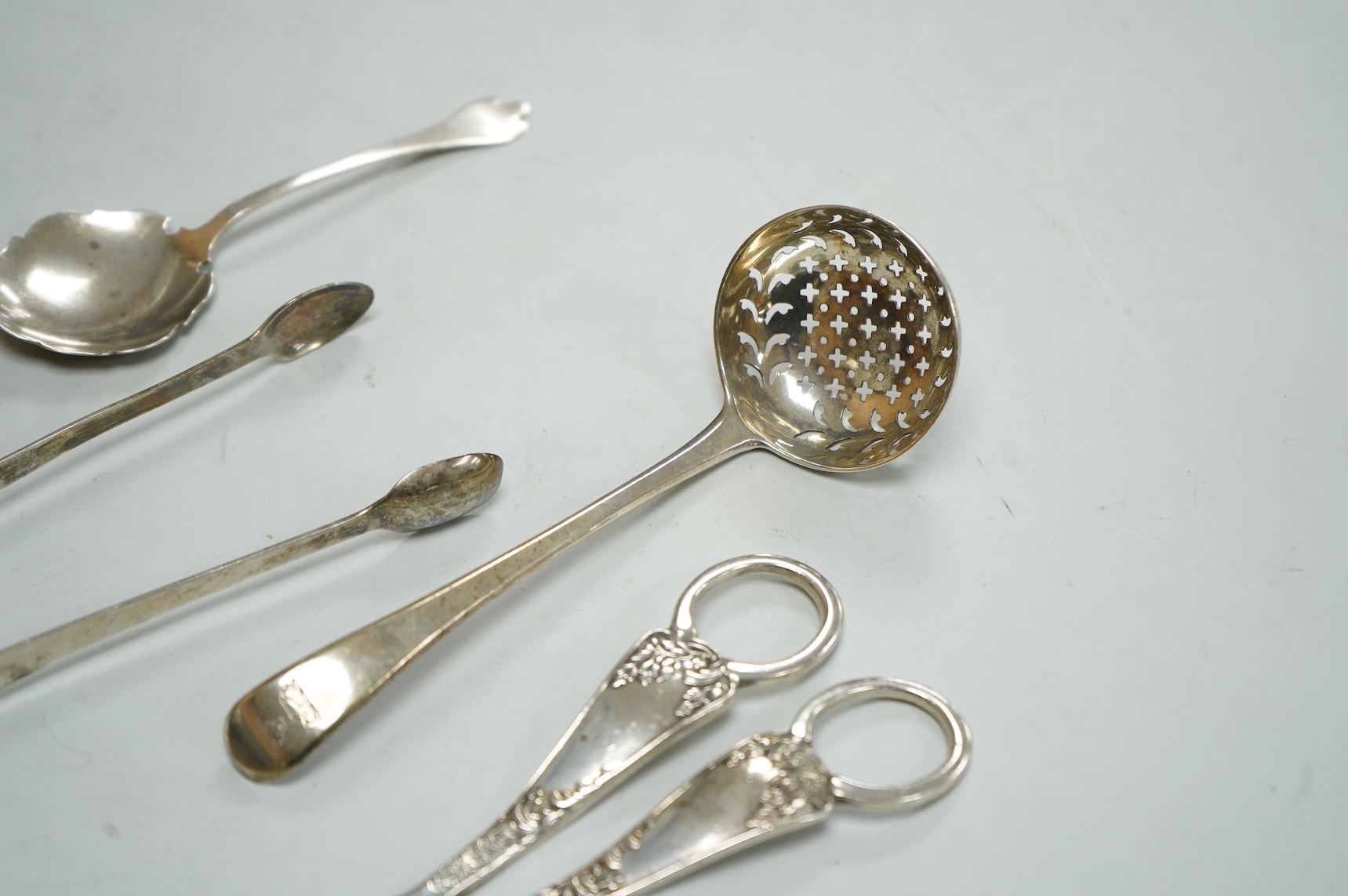 A pair of George V silver grape shears, Josiah Williams & Co, London, 1912, 16.2cm, together with a George III silver Old English pattern sifter spoon, Eley & Fearn, London, 1801, a similar pair of sugar tongs, London, 1